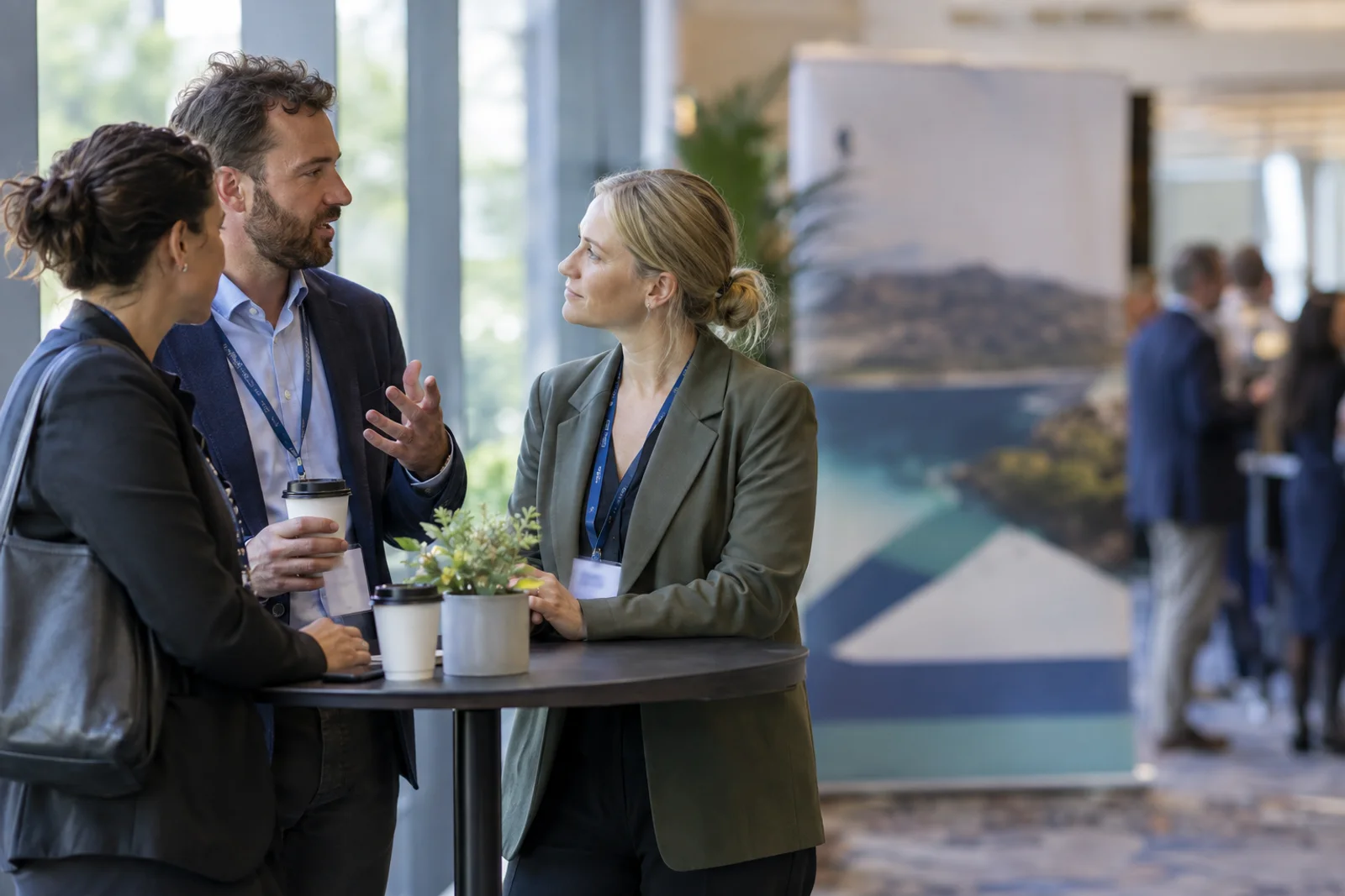 Three people from different organisations in conversation at a high table at an industry event.