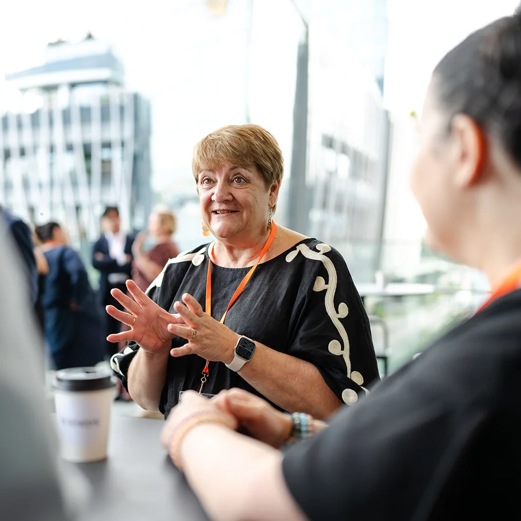 Event attendees in conversation, with a woman gesturing as she speaks.